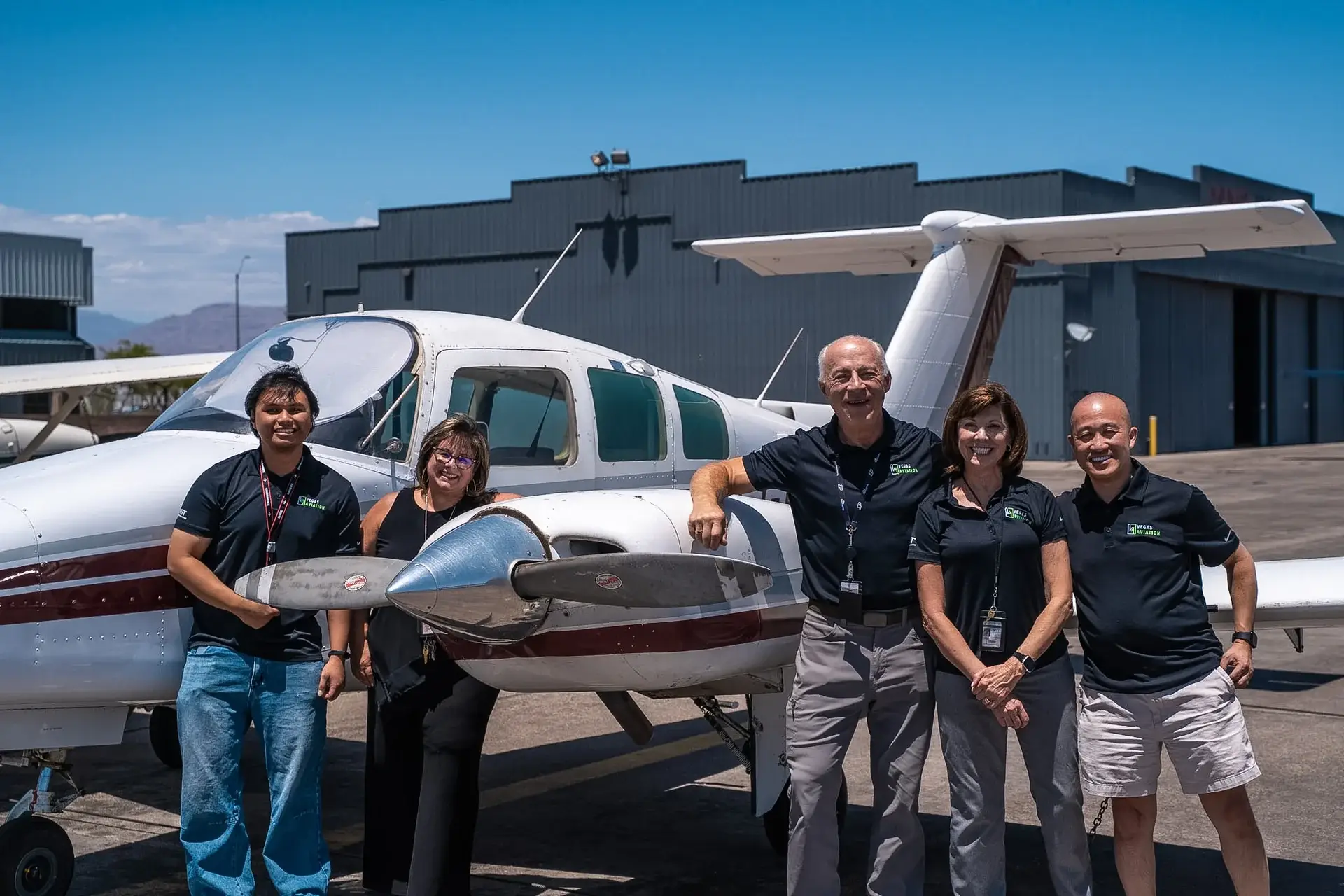 Vegas Aviation admin team in front of a Beechcraft Duchess multi-engine aircraft