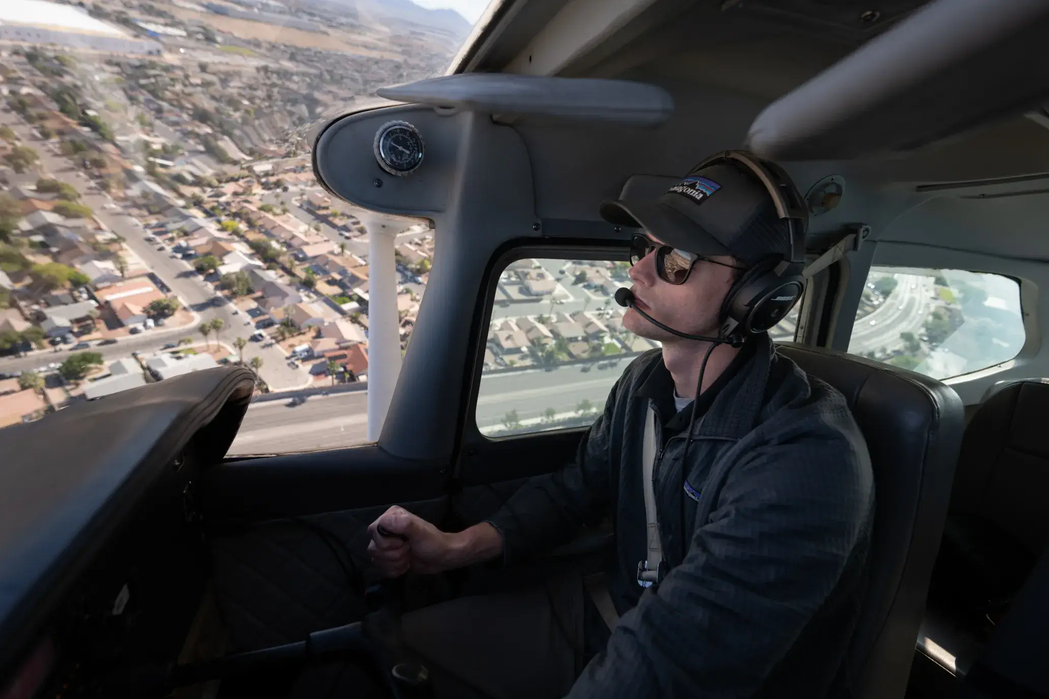 Pilot inside cockpit flying airplane above city