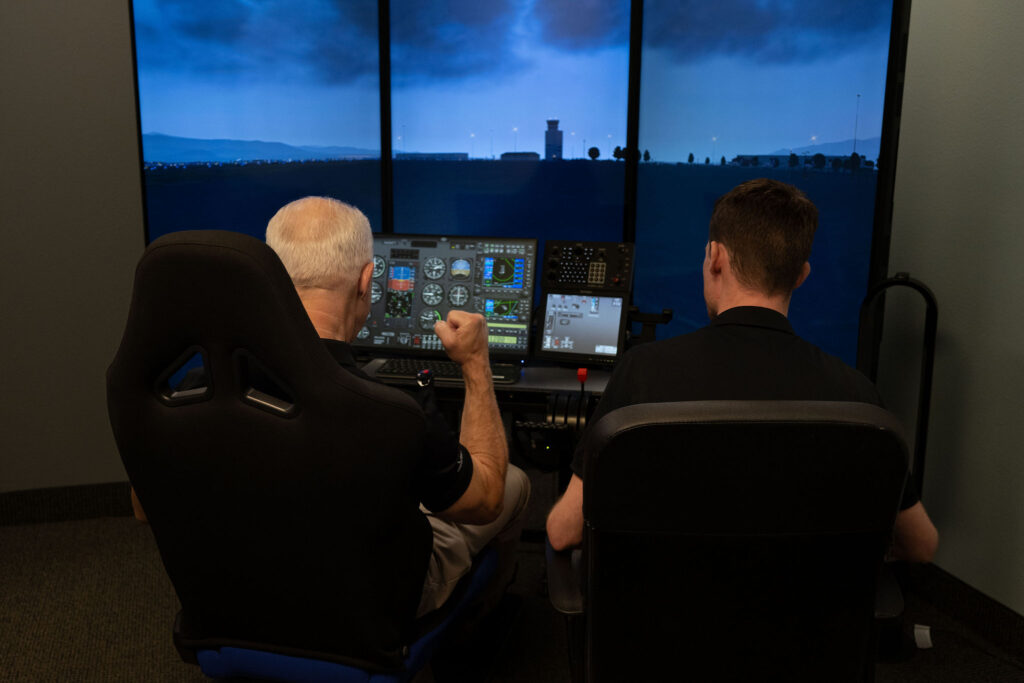 Backview of two men using Vegas Aviation's Flight Simulator