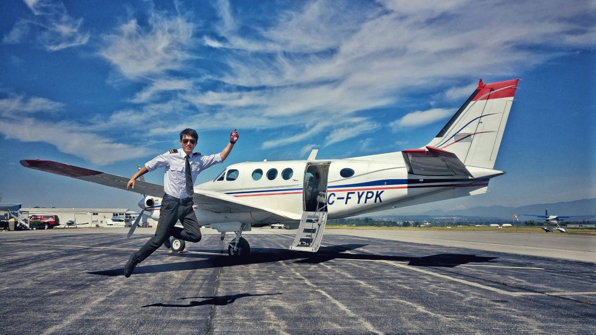 New pilot celebrating beside a twin-engine training aircraft after earning his wings